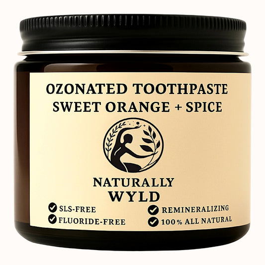 Amber glass jar of Naturally Wyld Ozonated Toothpaste in Sweet Orange + Spice flavour. Fluoride-free, SLS-free, 100% all-natural remineralizing toothpaste. Label highlights botanical formula with essential oils and natural whitening properties.