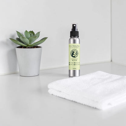 Bottle of natural product with a plant and towel on a white surface