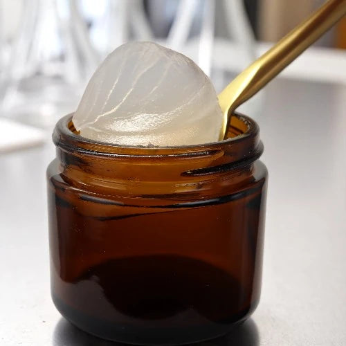 Scoop of ozonated sunflower oil in amber jar with golden spoon, showing translucent gel texture and premium ozone infusion for sensitive skin care.